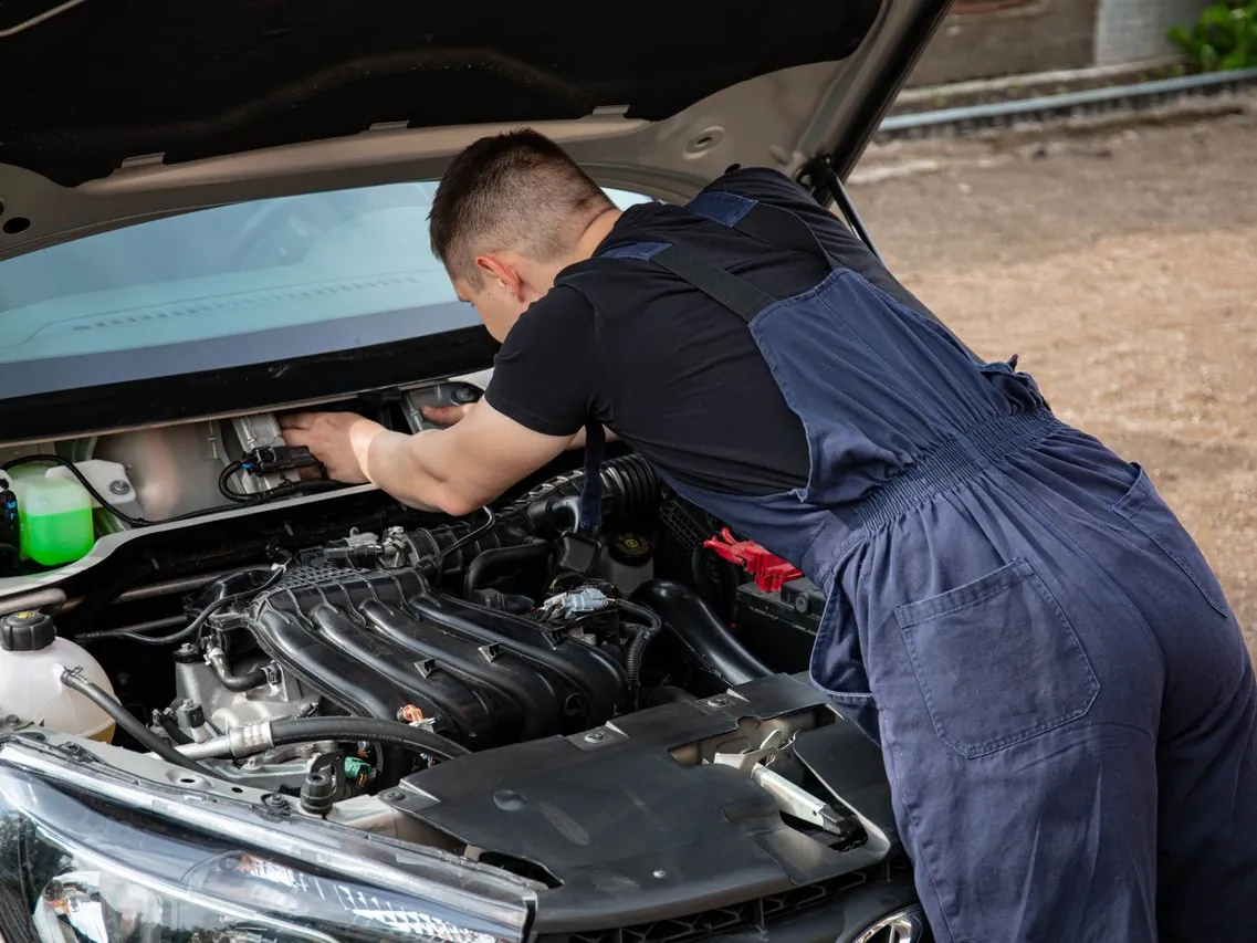 Mechanik kontroluje motor auta pod otevřenou kapotou